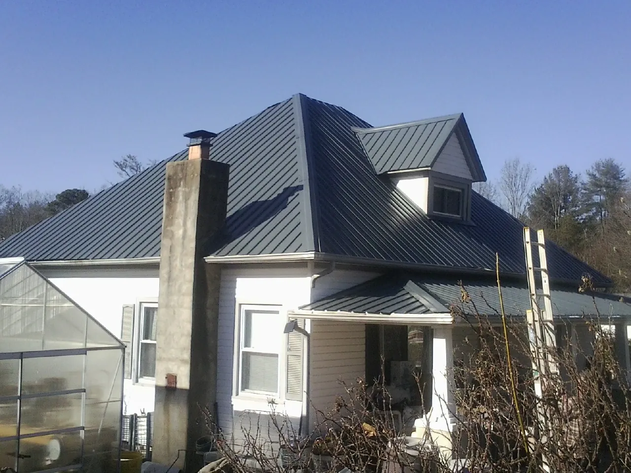Dark blue standing seam metal roof on a white farmhouse with dormer — Slate & Tile Roof Repair by Roofing Brothers in Nitro