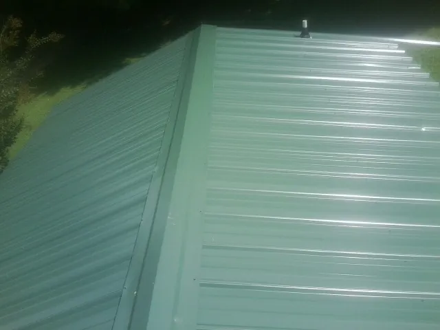 New green metal panels meeting at the ridge of a roof — Flat Roof Repair work by our crew in Nitro