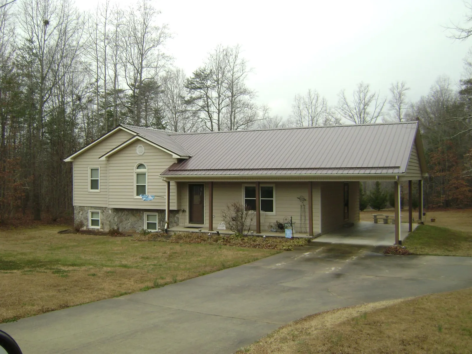 Brown metal roof on a tan split level home with an attached carport in Nitro