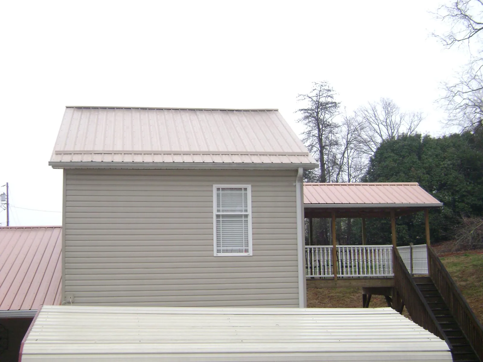 Tan metal roofs on a two story addition and attached porch, from a Roof Replacement job in Nitro