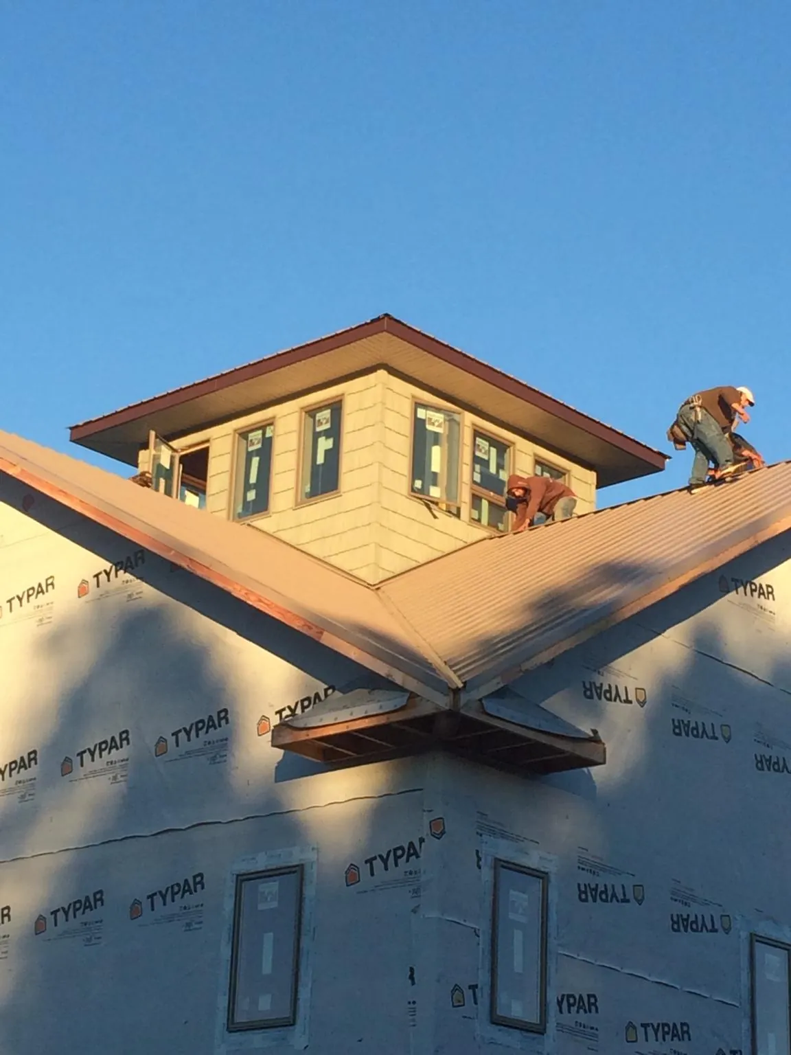 Roofers working around a rooftop cupola on a new metal roof at sunset — Roof Waterproofing in Nitro by Roofing Brothers
